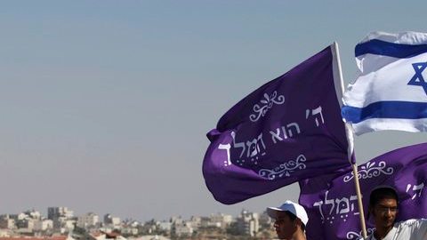 Judíos colonos ondean  banderas  mientras marchan hacia   un barrio del este de Jerusalén, donde los asentamientos están en el centro de la discordia.