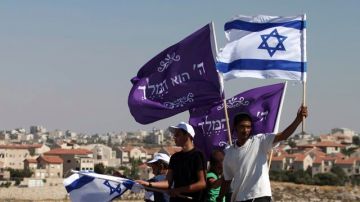 Judíos colonos ondean  banderas  mientras marchan hacia   un barrio del este de Jerusalén, donde los asentamientos están en el centro de la discordia.