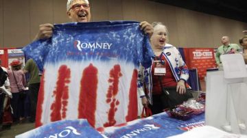 Favorecedores de Mitt Romney muestran unas camisetas con los colores patrios y el nombre de su candidato.