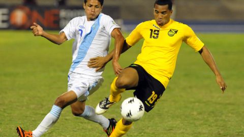El jamaiquino Adrian Mariappa (der.) controla el balón ante la marca del chapín Jairo Arreola, en acción del partido de anoche en Kingston.