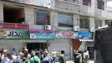 Agentes de seguridad inspeccionan zona donde explotó una bomba, mató a dos y dañó un vehículo.