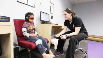 Miguel Barragán, de 5 años, recibe tratamiento visual y auditivo en un centro de Encino. Junto a él su terapista.