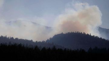 Un aeroplano vuela y atraviesa el humo del fuego de Springer cercano a Lake George, en Colorado.