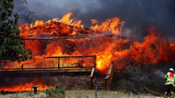 Un bombero lucha por apagar las llamas  que consumen una casa en Estes Park, Colorado.