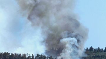 Un fuego, no controlado aún, quema parte de un bosque detrás de estas casas, al oeste de Colorado Springs, en Colorado, ayer.