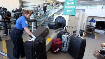 Agentes del aeropuerto hacen pasar  el equipaje por una máquina de rayos x para ver si hay  armas.