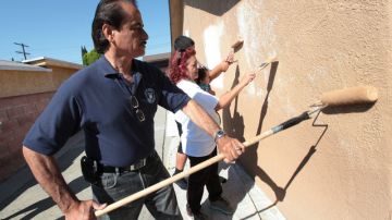 El concejal por el Séptimo Distrito, Richard Alarcón ayuda a Lupe Hernández a pintar el exterior de la casa de esta.