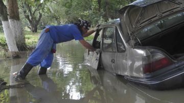 Un trabajador del ministerio examinando un coche hundido en el agua, en Krymsk, Krasnodar, Rusía, ayer.