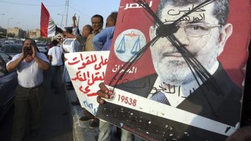 Los trabajadores egipcios tachan la imagen del presidente Mohamed Mursi durante una manifestación para pedir una mejora en sus condiciones laborales, ayer.