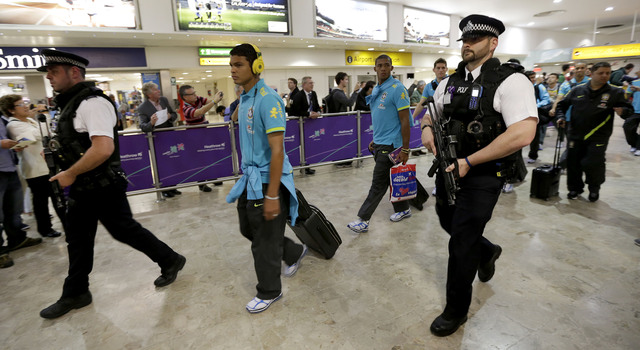Miembros del equipo de futbol olímpico de Brasil son escoltados por dos guardias a su llegada al Aeropuerto Heathrow.