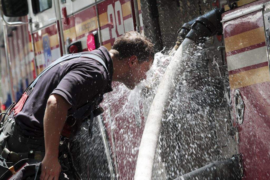 Un bombero se refresca del calor en una calle de Manhattan.