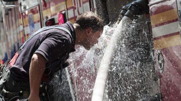 Un bombero se refresca del calor en una calle de Manhattan.