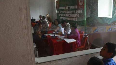 Niños estadounidenses observan como varias familias tratan de obtener el sello mexicano en los certificados de nacimiento de EEUU.