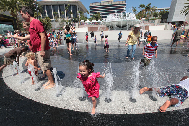 Los niños corretean y  juegan felices con los chorros de agua en los alrededores de la fuente principal de Grand Park.