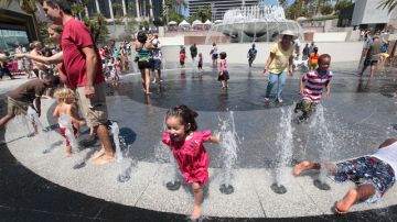 Los niños corretean y  juegan felices con los chorros de agua en los alrededores de la fuente principal de Grand Park.