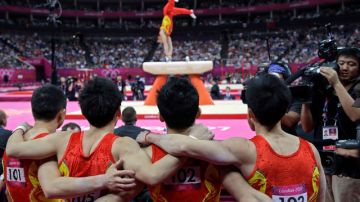 Los gimnastas chinos observan a su compañero en su actuación en el potro durante la final de ayer de la prueba en la que conquistaron el  oro.