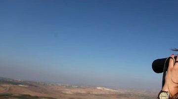 Una mujer israelí se ve usando  unos prismáticos desde la región de Bukata, en los Altos del Golán, Israel, en la frontera con Siria.