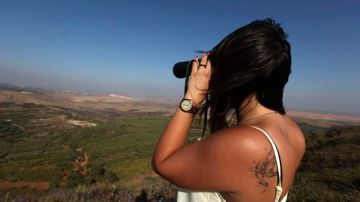 Una mujer israelí se ve usando  unos prismáticos desde la región de Bukata, en los Altos del Golán, Israel, en la frontera con Siria.