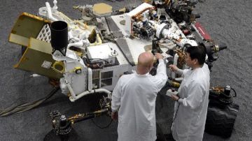 Los ingenieros James Wong (d) y Errin Balshaug (i) examinan el prototipo del vehículo Mars rover.