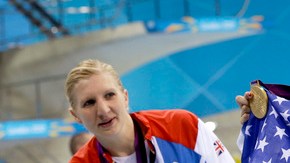 Katie Ledecky presume medalla de oro y bandera tras ganar   los 800 metros libres; la observa Rebecca Adlington.