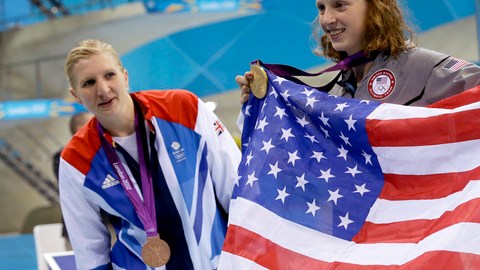 Katie Ledecky presume medalla de oro y bandera tras ganar   los 800 metros libres; la observa Rebecca Adlington.