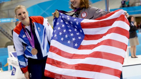 Katie Ledecky presume medalla de oro y bandera tras ganar los 800 metros libres; la observa Rebecca Adlington.