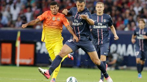 El delantero del PSG, Zlatan Ibrahimovic, conduce el balón ante la  marca del jugador del Barcelona, Rafinha Alcántara.