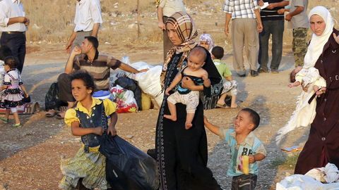 Refugiados sirios, que huyeron de la violencia en su país, hacen cola en la frontera siria con Turquía, en Hatay.