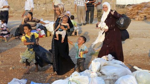 Refugiados sirios, que huyeron de la violencia en su país, hacen cola en la frontera siria con Turquía, en Hatay.