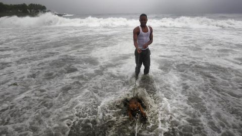 Un hombre pasea con su perro en el mar donde se registra fuerte oleaje por el paso de la tormenta tropical Ernesto ayer.