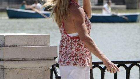 Una mujer que pasea junto al estanque de El Retiro de Madrid se protege del sol.