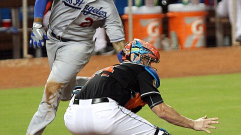 Matt Kemp, (izq.) se prepara para anotar, mientras el receptor de los Marlins,  John Buck, pierde la pelota en jugada del sexto inning.