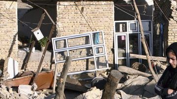 Dos hermanos caminan sobre los escombros de su vivienda en la aldea de Bajeh Baj, después de los dos fuertes terremotos.