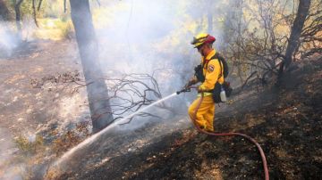 Un bombero trabaja en apagar una llamarada en el fuego de Wye, cerca de Clearlake Oaks, California.