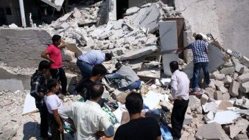 Un grupo de personas busca víctimas entre los escombros tras un bombardeo aéreo de las fuerzas gubernamentales de Bachar el Asad ocurrido ayer en Azaz, Siria.