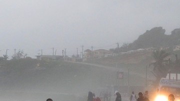 La gente corre sobre un puente golpeado por fuertes olas, debido a la tormenta tropical 'Isaac', en República Dominicana, ayer.
