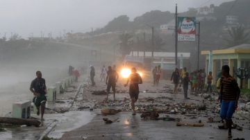La gente corre sobre un puente golpeado por fuertes olas, debido a la tormenta tropical 'Isaac', en República Dominicana, ayer.