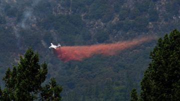 Aviones cisterna ayudan en el combate a las llamas que amenazan extenderse a una zona boscosa.