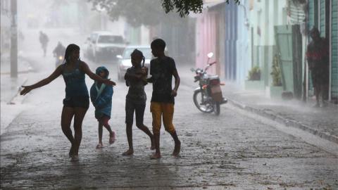 Niños caminan bajo la intensa lluvia, durante el paso de la tormenta tropical "Isaac" en Enriquillo, República Dominicana.