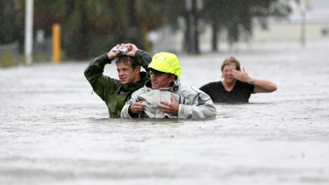 Chuck Cropp, al centro, su hijo Piers y su esposa Liz, tratan de atravesar por una de las calles inundadas de Nueva Orleáns.