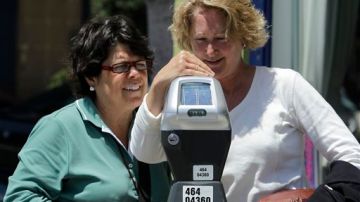 Unas mujeres colocan dinero en un parquímetro de San Francisco.