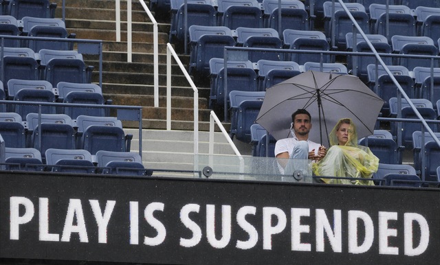 Aficionados esperan bajo la lluvia la reanudación del partido entre  Stosur y Azarenka que tuvo que ser suspendido 76 minutos.