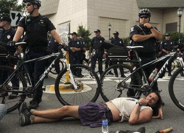 Un hombre se acuesta en el piso durante una protesta, mientras los policías custodian la inauguración de la convención del Partido Demócrata.