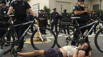 Un hombre se acuesta en el piso durante una protesta, mientras los policías custodian la inauguración de la convención del Partido Demócrata.