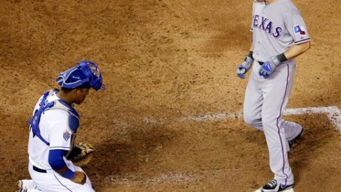 Michael Young de los Rangers cruza el home frente a Salvador Pérez de los Reales.