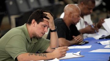 Un grupo de desempleados llena solicitudes de empleo en una feria de empleos de Nueva York.