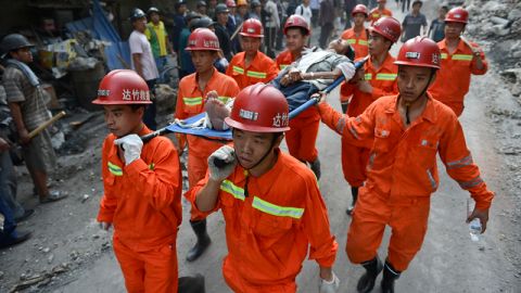 Rescatistas transportan a una víctima herida por uno de los terremotos en el pueblo de Luozehe, en Yiliang.