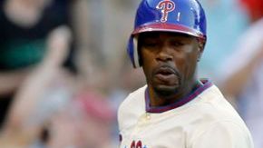 Jimmy Rollins de los Filis anota frente al catcher de los Marlins, John Buck, para conseguir el séptimo triunfo al hilo.