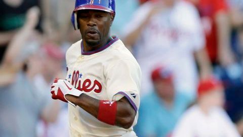Jimmy Rollins de los Filis anota frente al catcher de los Marlins, John Buck, para conseguir el séptimo triunfo al hilo.