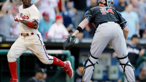 Jimmy Rollins de los Filis anota frente al catcher de los Marlins, John Buck, para conseguir el séptimo triunfo al hilo.